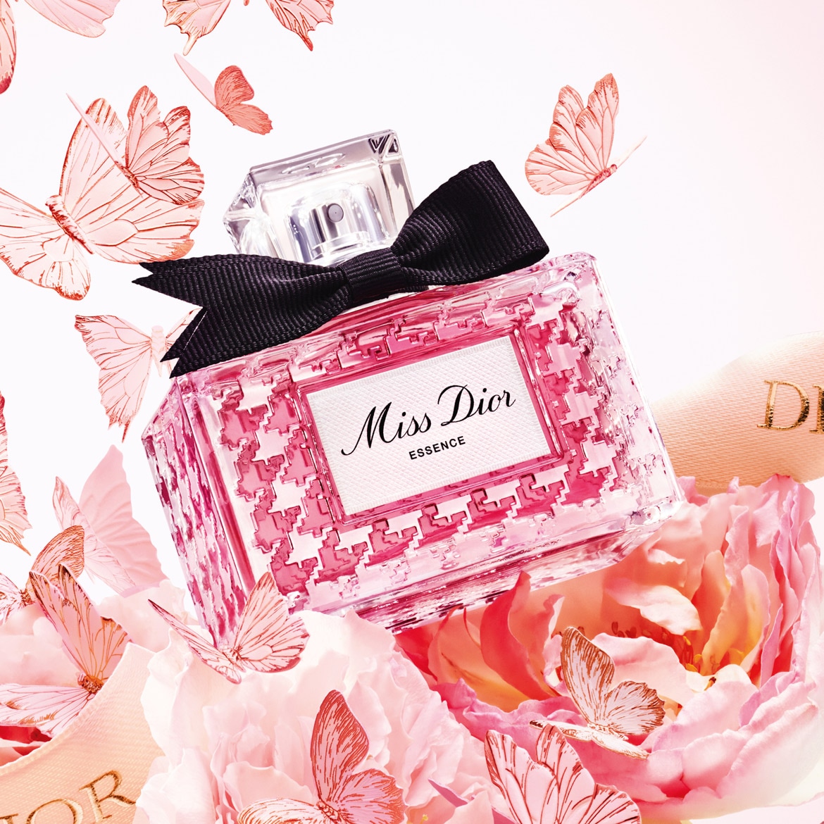 Découvrez Miss Dior Essence, un parfum floral et pétillant dans un flacon rose orné d'un nœud noir, entouré de papillons délicats et de pivoines roses.