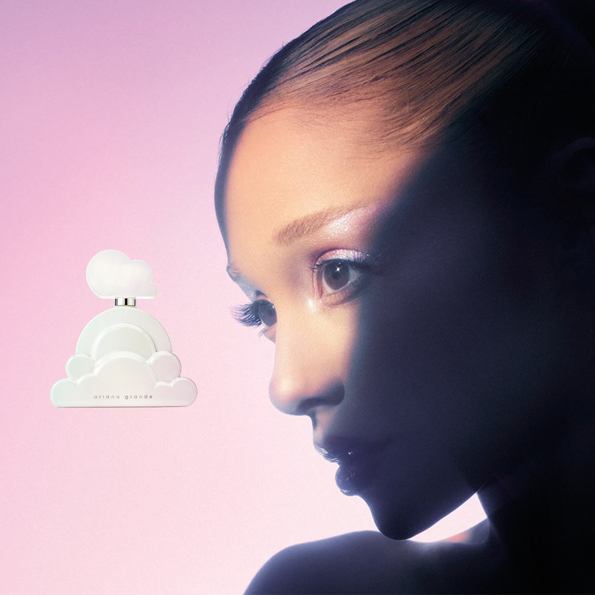Ariana Grande Cloud Eau de Parfum, un flacon blanc en forme de nuage avec le nom de la marque en noir, est présenté à côté du visage d'Ariana Grande, dont la moitié est éclairée par une lumière rose et l'autre moitié est dans l'ombre.