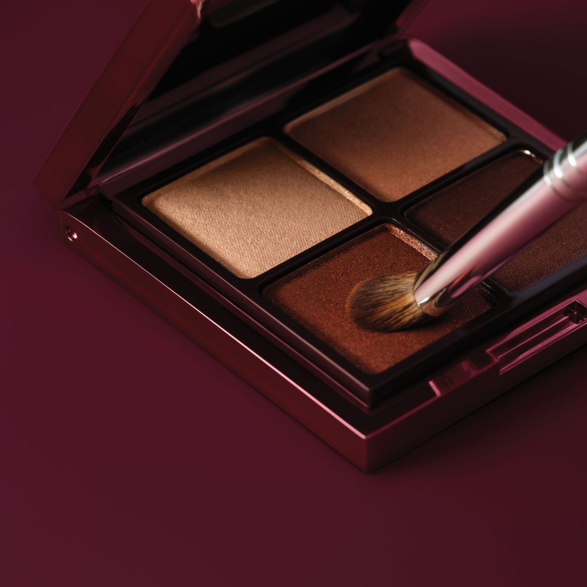Une palette de fards à paupières marron et or avec un pinceau, offrant des teintes chaudes pour un regard intense et sophistiqué.