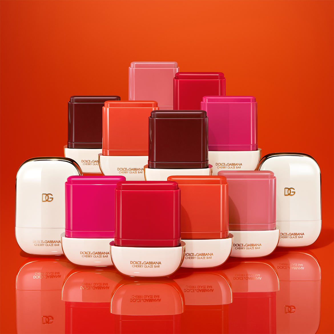 Découvrez Dolce&Gabbana Cherry Glaze Bar, une collection de baumes à lèvres teintés aux couleurs allant du rose au rouge foncé, présentés dans des étuis blancs élégants avec le logo DG.