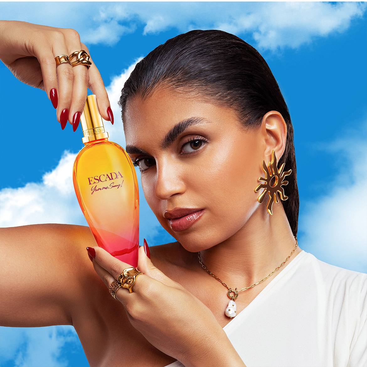 Une femme tient un parfum Escada 'Yumme Sunny' avec un flacon dégradé jaune-rose, évoquant une ambiance ensoleillée et estivale.