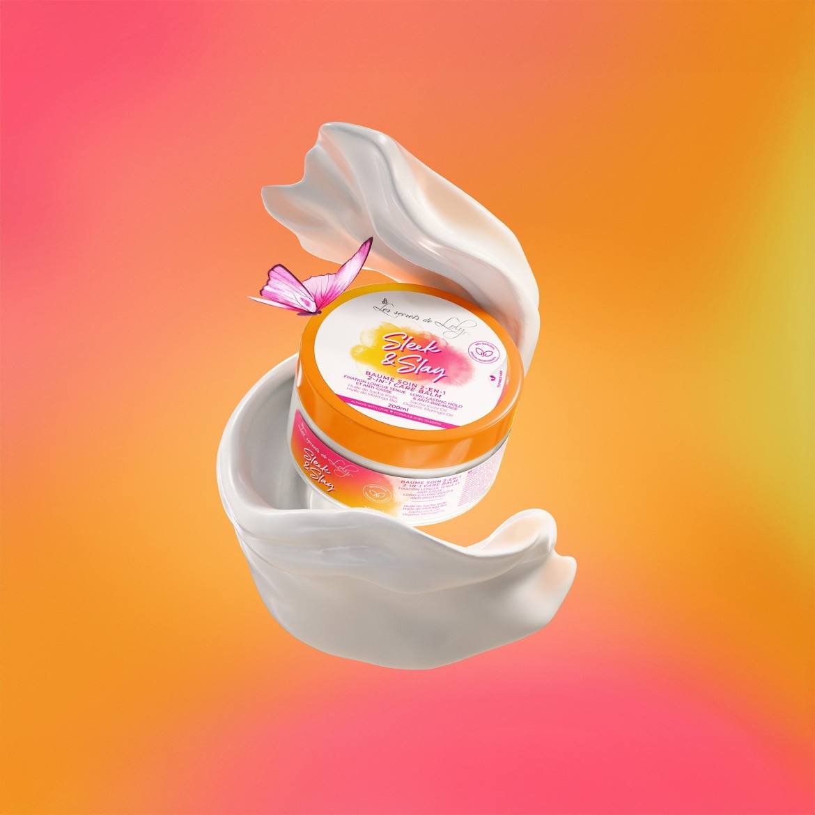 Le baume capillaire Sleek & Slay 2-en-1 de Les secrets de Loly, dans un pot orange et blanc de 200 ml, est mis en valeur par un ruban blanc fluide et un papillon rose, sur un fond dégradé d'orange et de rose.