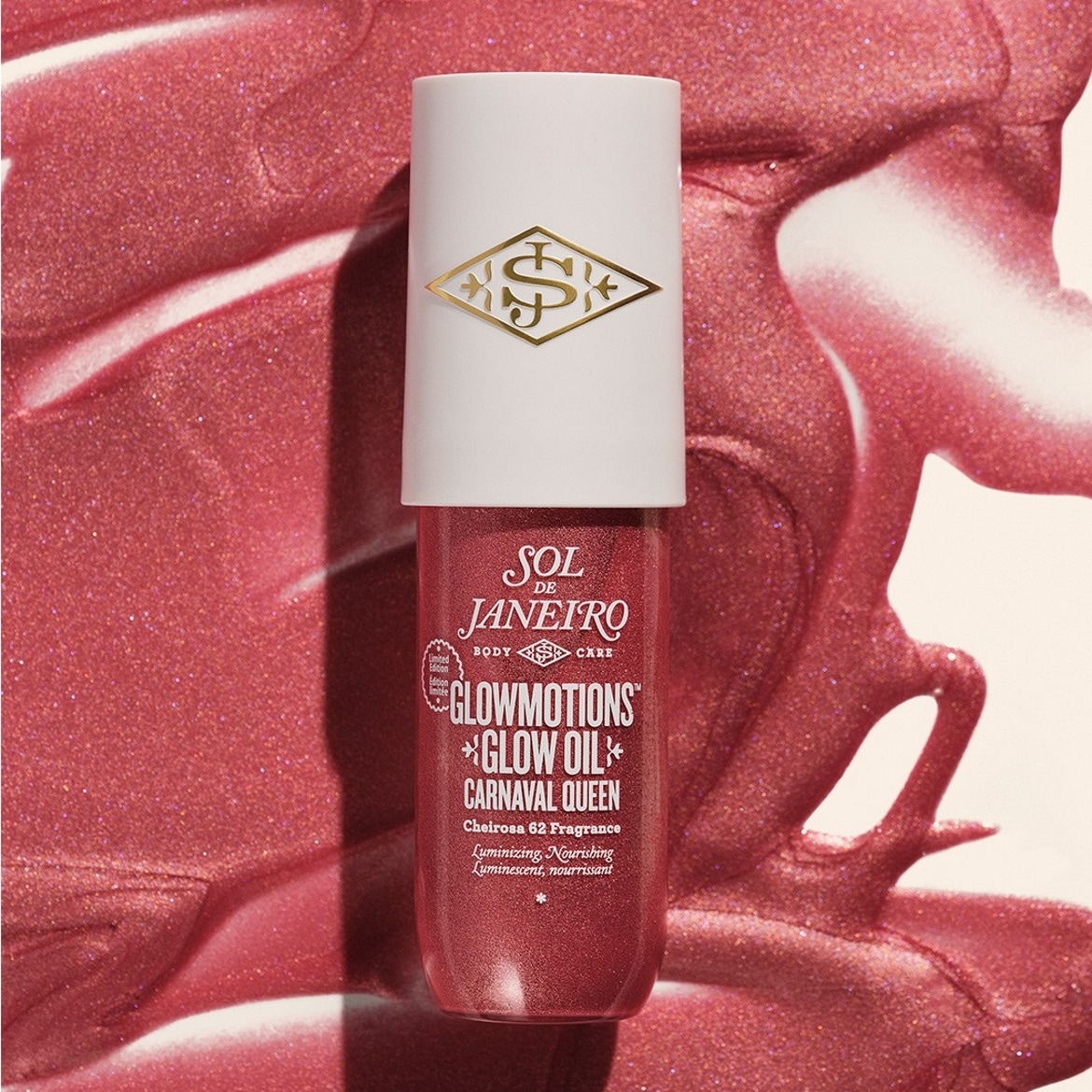 Le flacon de Sol de Janeiro Glowmotions Glow Oil Carnaval Queen, une huile scintillante pour le corps, est posé sur un fond rose pailleté, mettant en valeur son éclat lumineux et nourrissant.