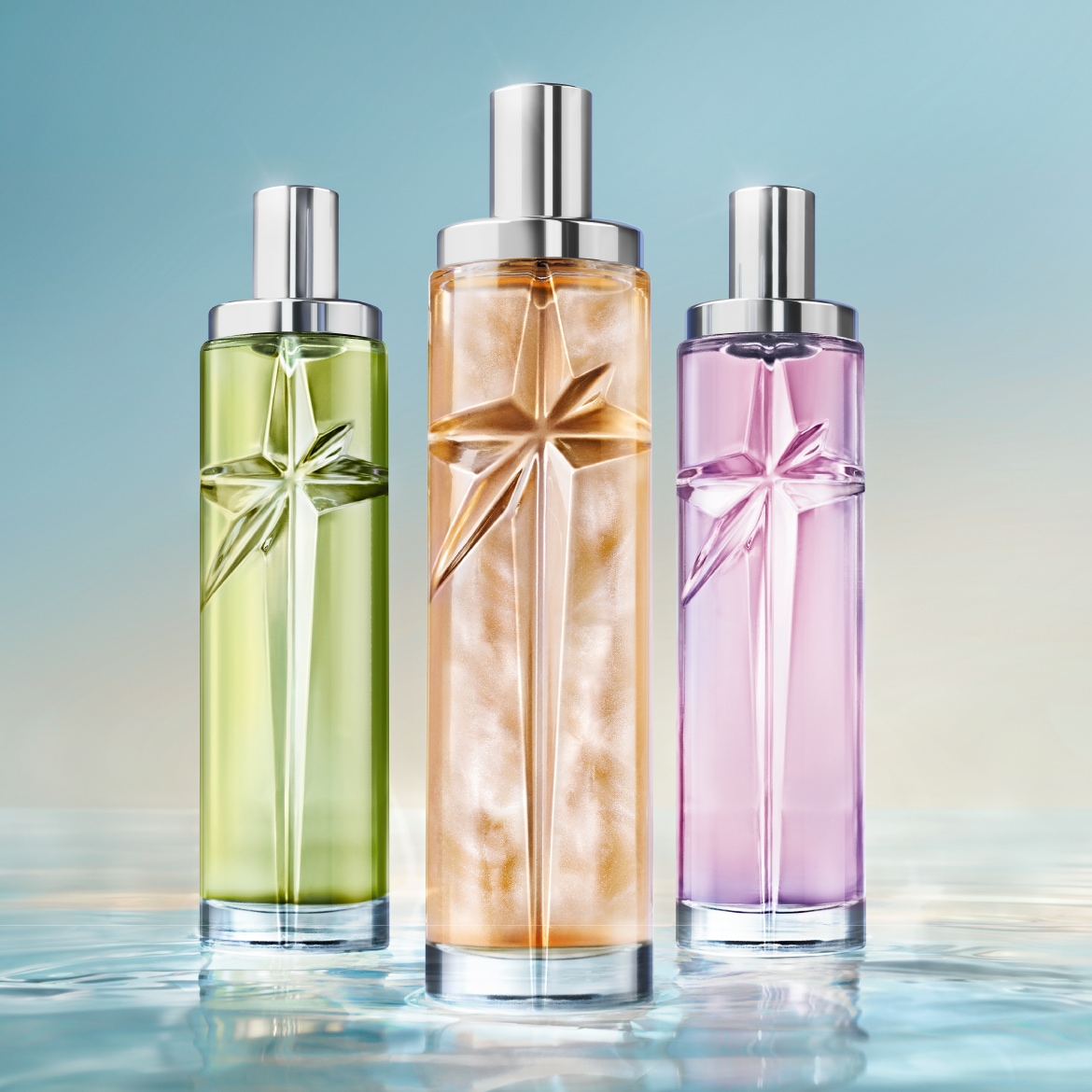 Trois flacons de parfum Angel de Mugler, aux teintes verte, orange et violette, avec un motif d'étoile en relief, reposent sur une surface d'eau scintillante.