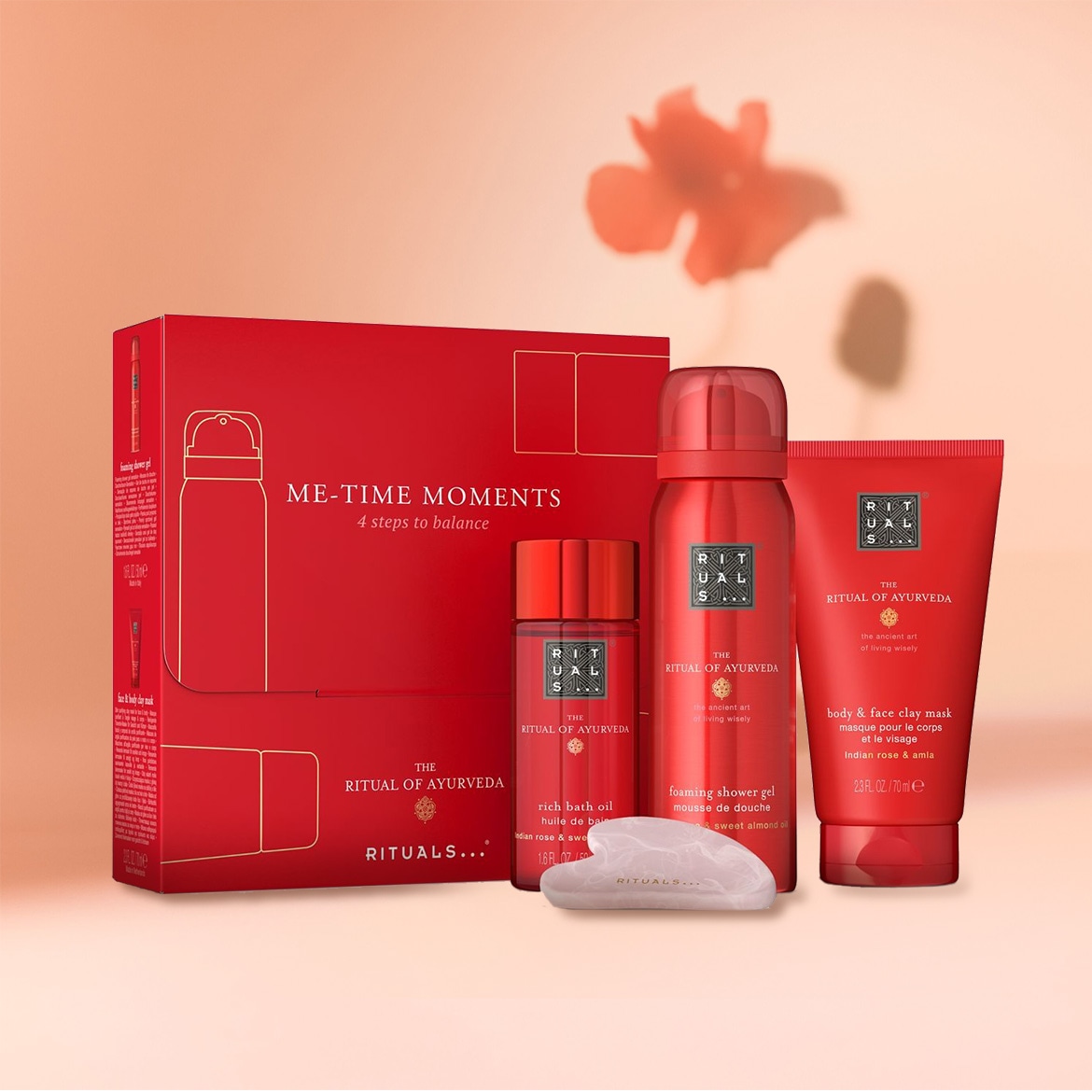 Découvrez le coffret cadeau Ritual of Ayurveda de Rituals, comprenant un gel douche moussant, une huile de bain riche, un masque à l'argile pour le corps et le visage, et une pierre de massage Gua Sha, le tout dans un emballage rouge.