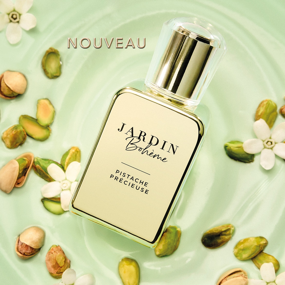 Découvrez le nouveau parfum Jardin Bohème Pistache Précieuse, une fragrance exquise présentée dans un flacon élégant, entourée de pistaches et de délicates fleurs blanches sur un fond vert clair.