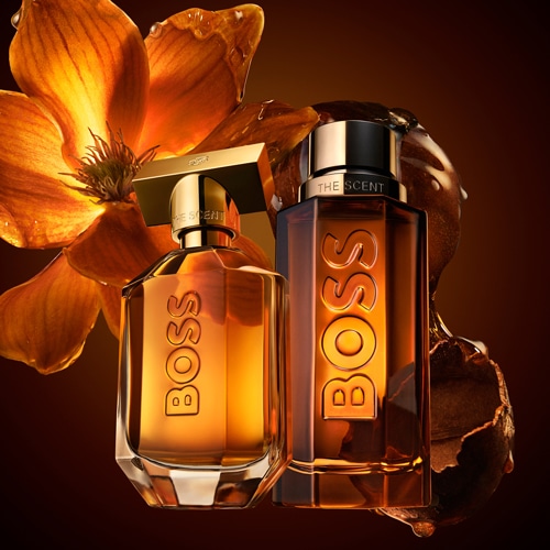 Découvrez le parfum BOSS The Scent, présenté dans des flacons élégants aux tons ambrés, rehaussés d'une fleur délicate.