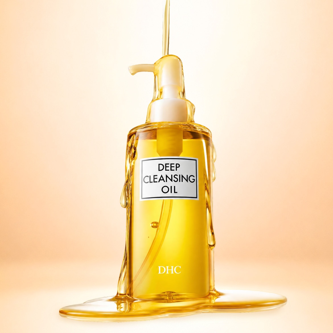 Le flacon pompe transparent de l'huile démaquillante DHC Deep Cleansing Oil, rempli d'un liquide doré, est mis en valeur par un filet d'huile qui s'écoule sur ses parois et forme une flaque à sa base.