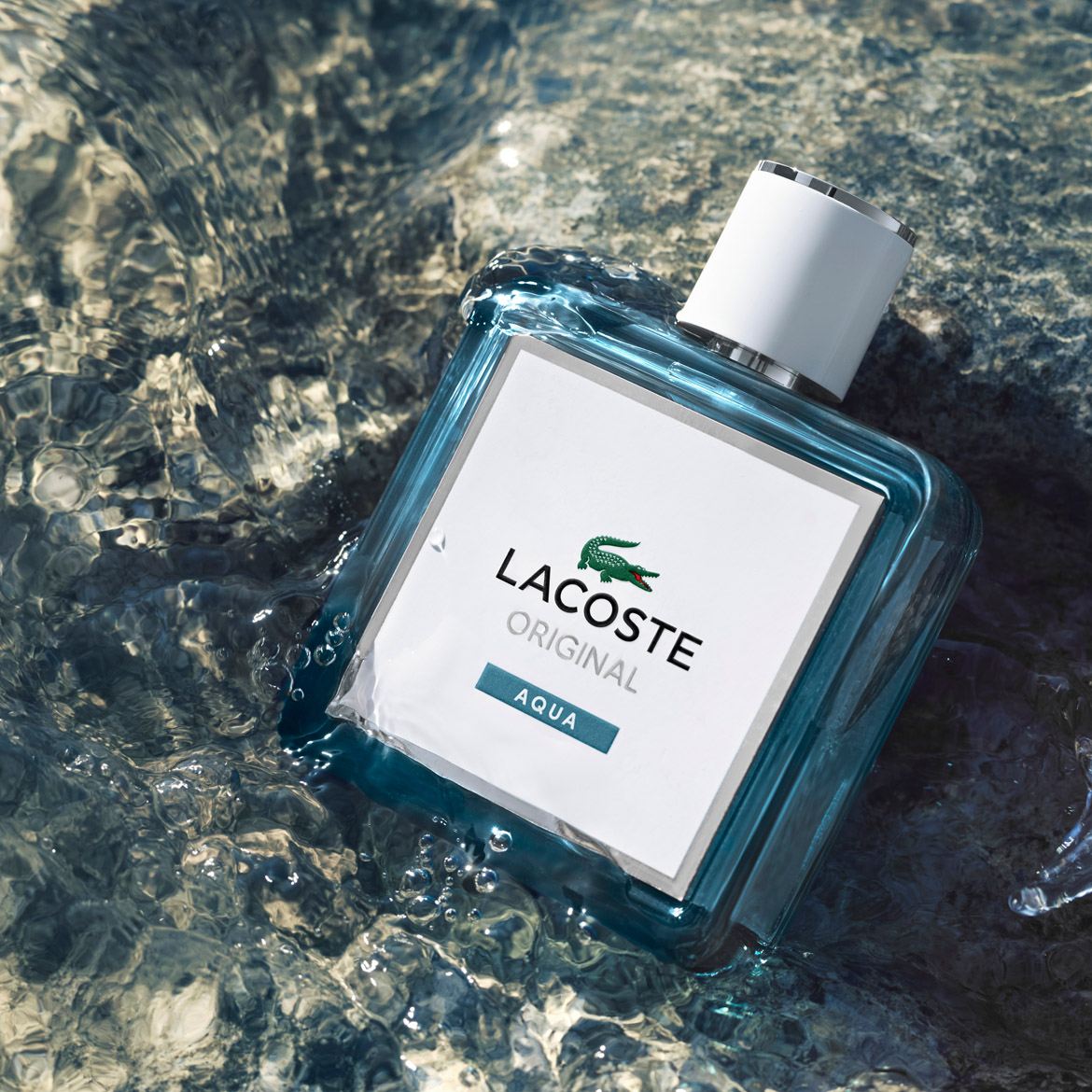 Découvrez Lacoste Original Aqua, un parfum frais dans un flacon bleu transparent, flottant sur l'eau, avec un bouchon blanc et le logo emblématique du crocodile vert.