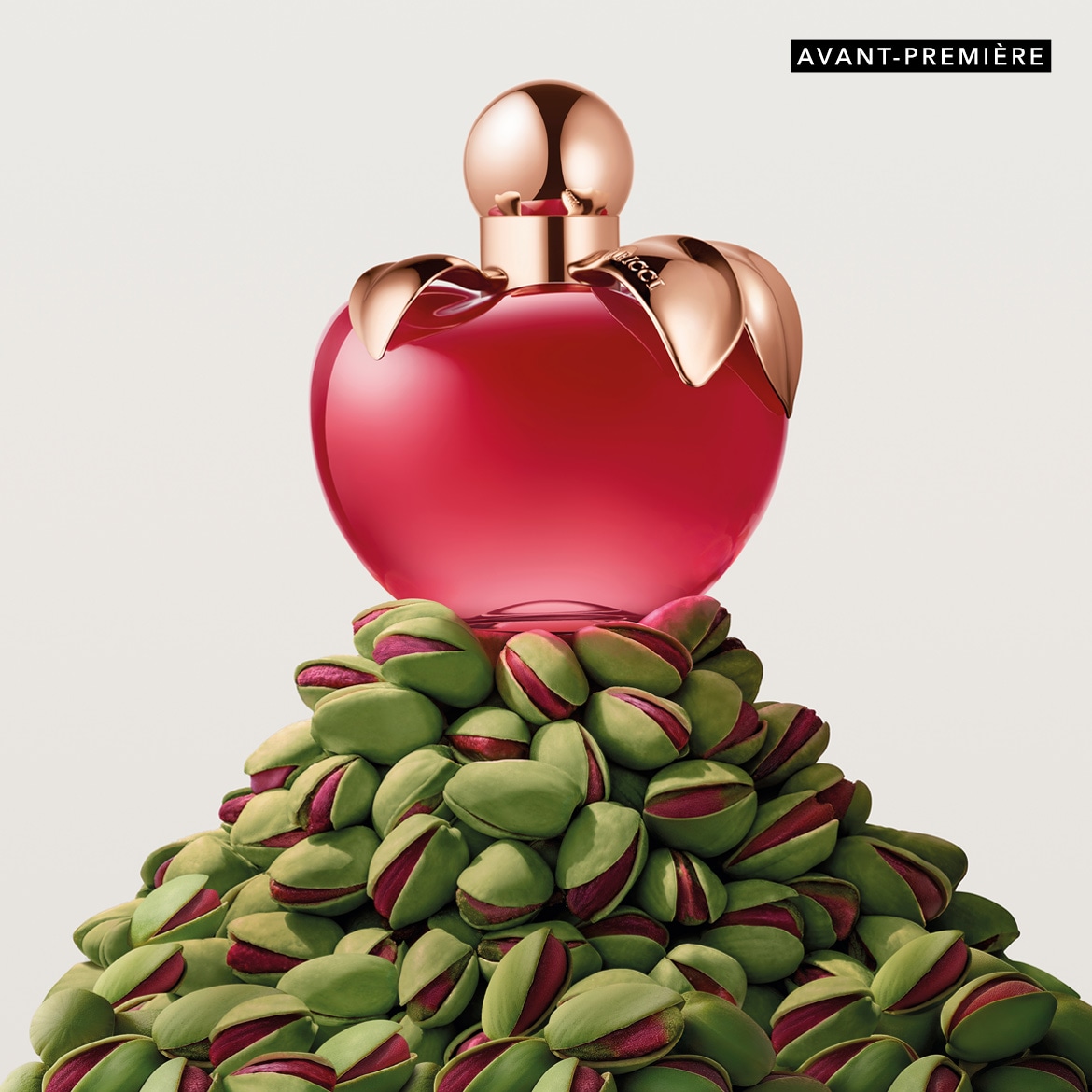 Découvrez le parfum Nina Ricci, présenté dans un flacon rouge en forme de pomme, sur un lit de pistaches vertes, une avant-première olfactive à ne pas manquer.