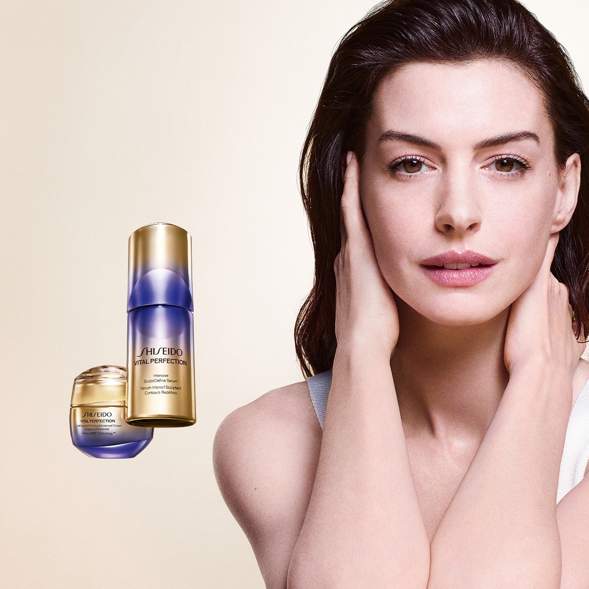 Une femme aux cheveux bruns et à la peau claire, vêtue d'un débardeur blanc, pose avec les mains sur le cou et la mâchoire, à côté de deux produits Shiseido Vital Perfection, un sérum et une crème, aux emballages dorés et violets.