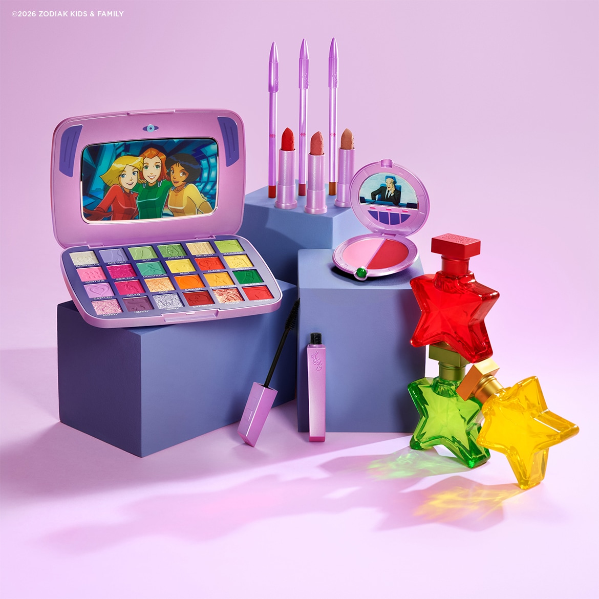La palette de fards à paupières Totally Spies, présentée dans un étui violet en forme d'ordinateur portable, révèle 18 teintes vibrantes, allant du mat au scintillant, avec un miroir affichant les personnages de la série.