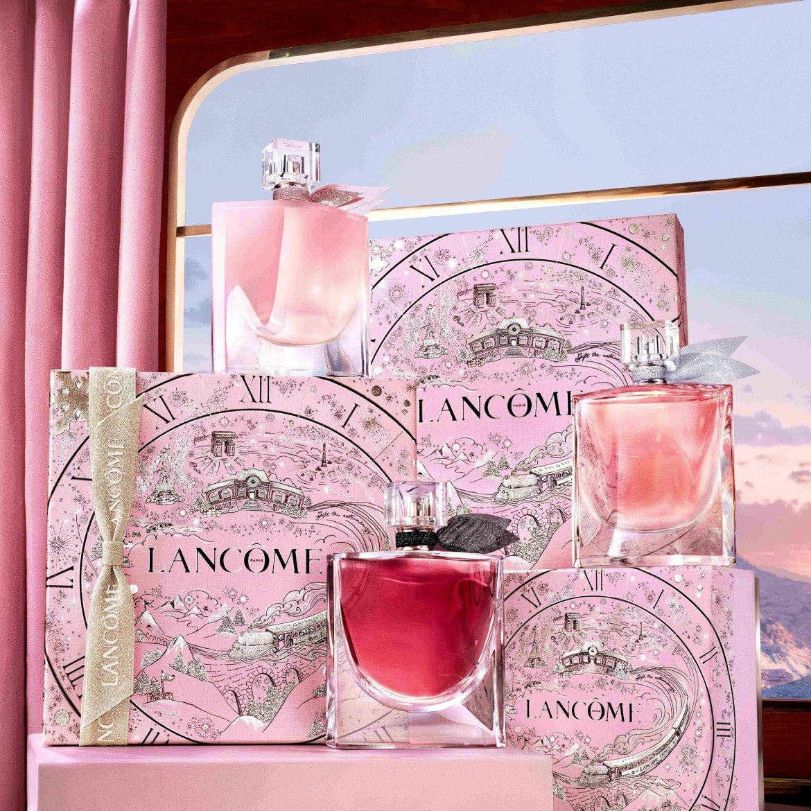 Découvrez un assortiment de parfums Lancôme dans des flacons aux teintes rosées, présentés sur des boîtes décorées de motifs romantiques.