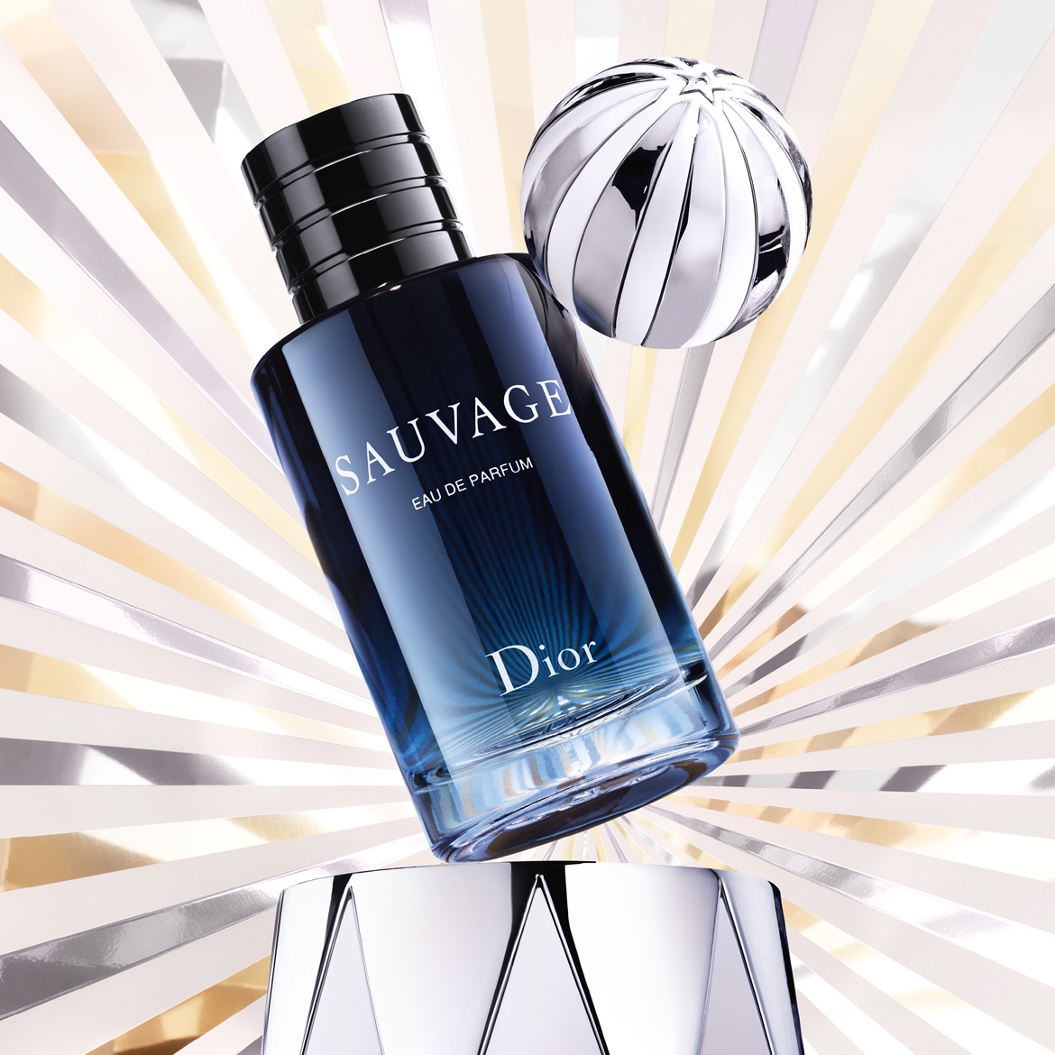 'Admirez Sauvage Eau de Parfum de Dior, un parfum masculin intense dans son flacon bleu nuit dégradé, sublimé par un fond argenté et une sphère décorative.