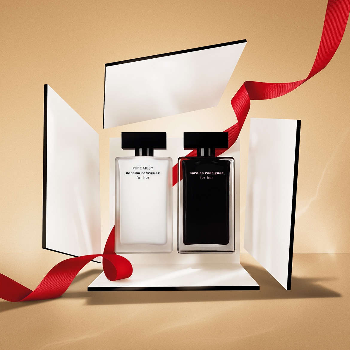 Découvrez le duo de parfums Narciso Rodriguez For Her, présentés dans des flacons noir et blanc épurés, rehaussés d'un ruban rouge festif.