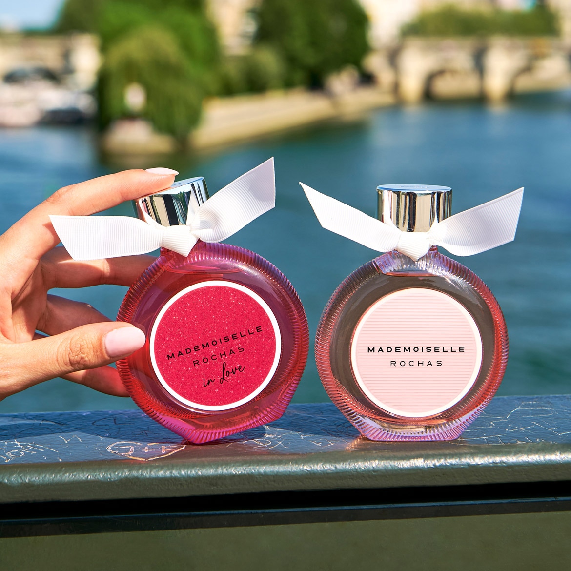 Découvrez Mademoiselle Rochas In Love, un parfum floral fruité pétillant dans un flacon rose orné d'un ruban blanc.