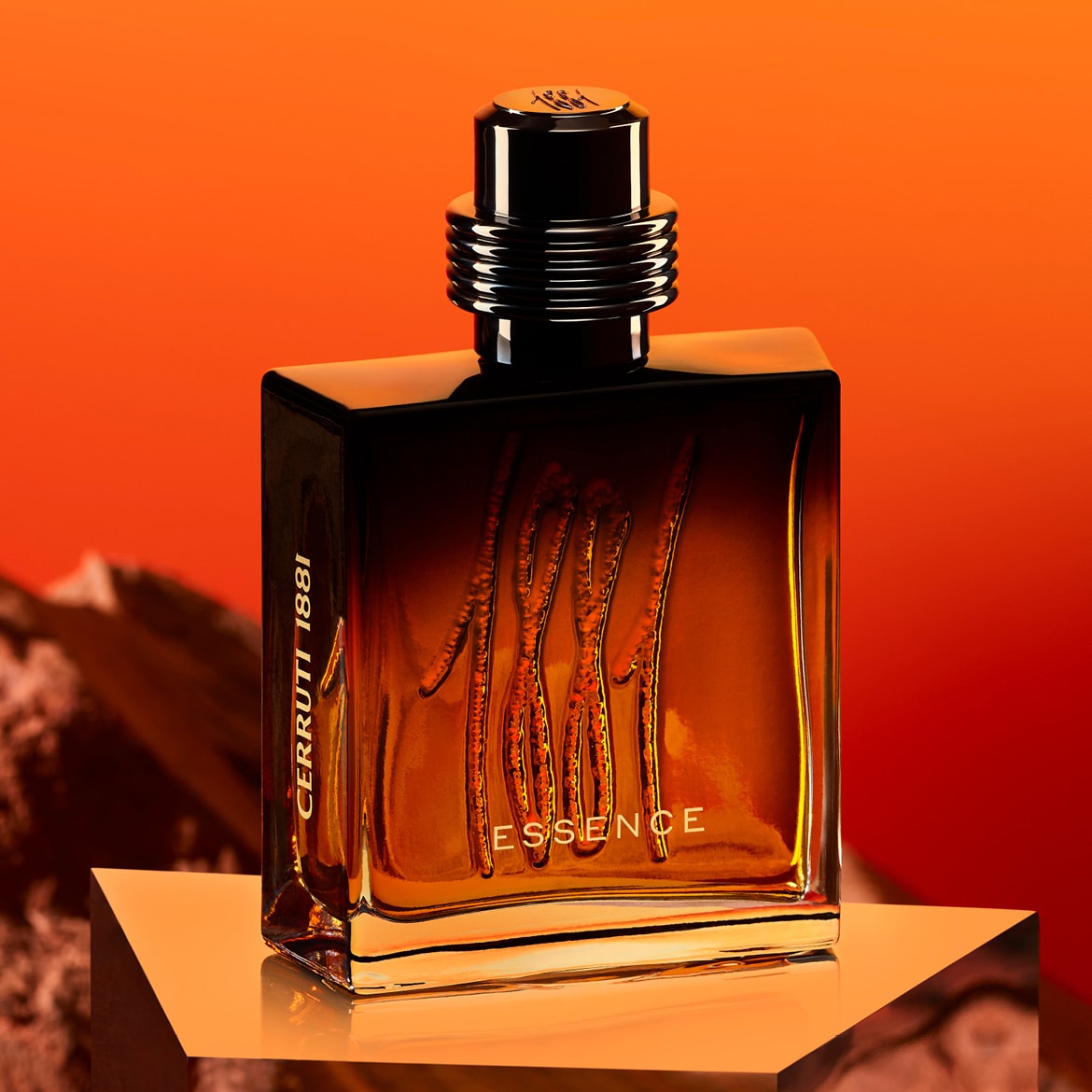 Le parfum Cerruti 1881 Essence est présenté dans un flacon rectangulaire en verre teinté ambre, avec un bouchon noir cannelé, sur un fond orange vif.