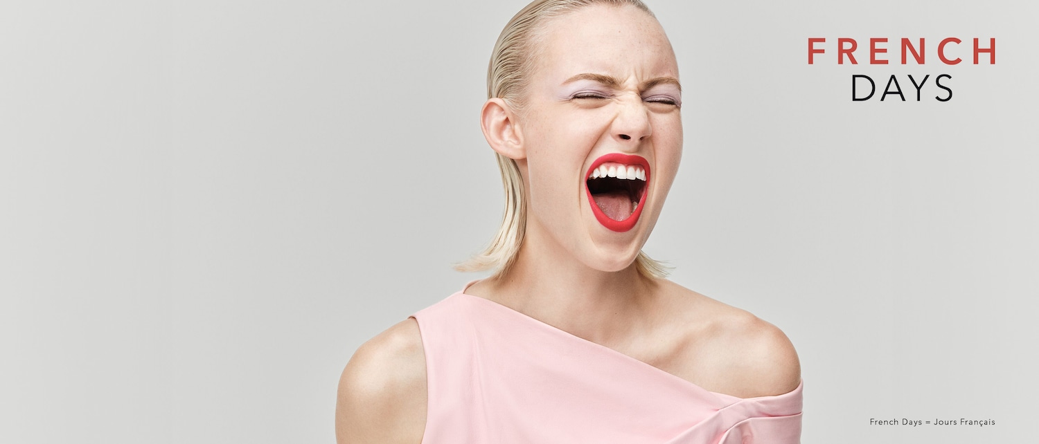 Une femme blonde, les yeux fermés et la bouche ouverte, porte un rouge à lèvres rouge vif et une robe rose pâle, avec le texte "FRENCH DAYS" en rouge et noir.