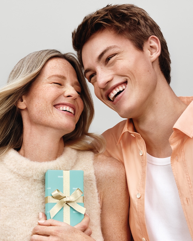 Mère et fils souriant, elle tient un cadeau turquoise orné d'un ruban doré, symbolisant l'amour et la gratitude pour la fête des Mères.