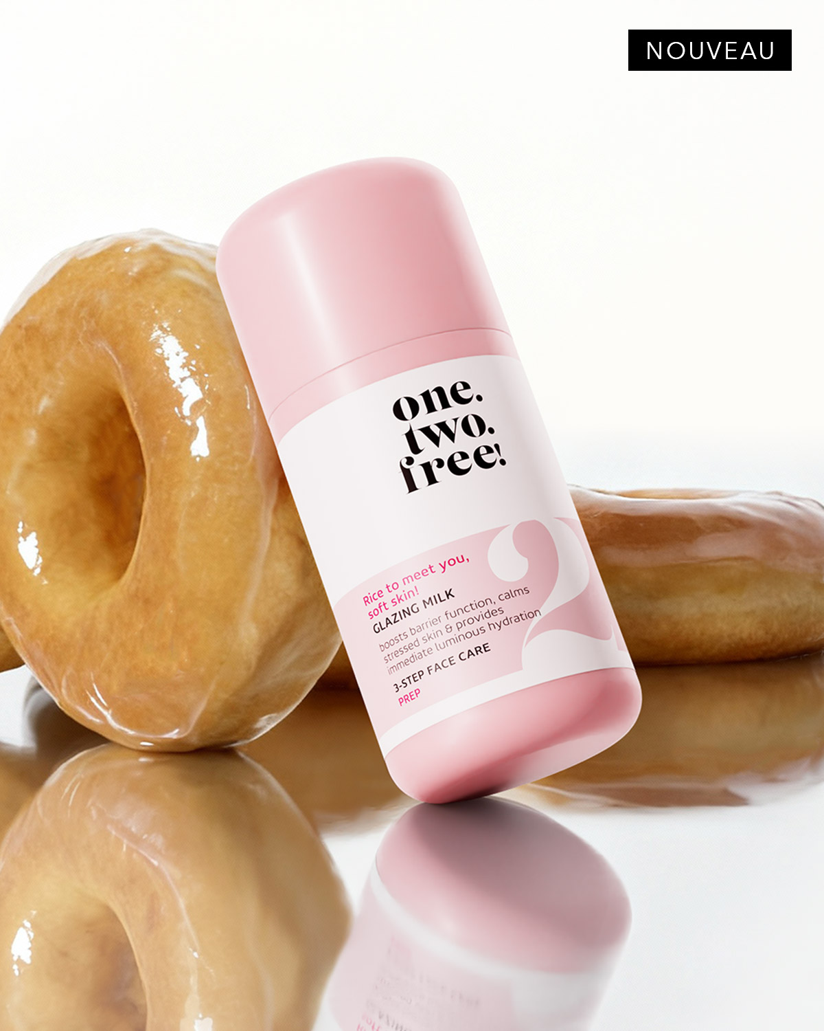 Découvrez le nouveau lait glacé One Two Free ! pour une peau douce et éclatante, présenté dans un flacon rose et blanc à côté de beignets glacés.