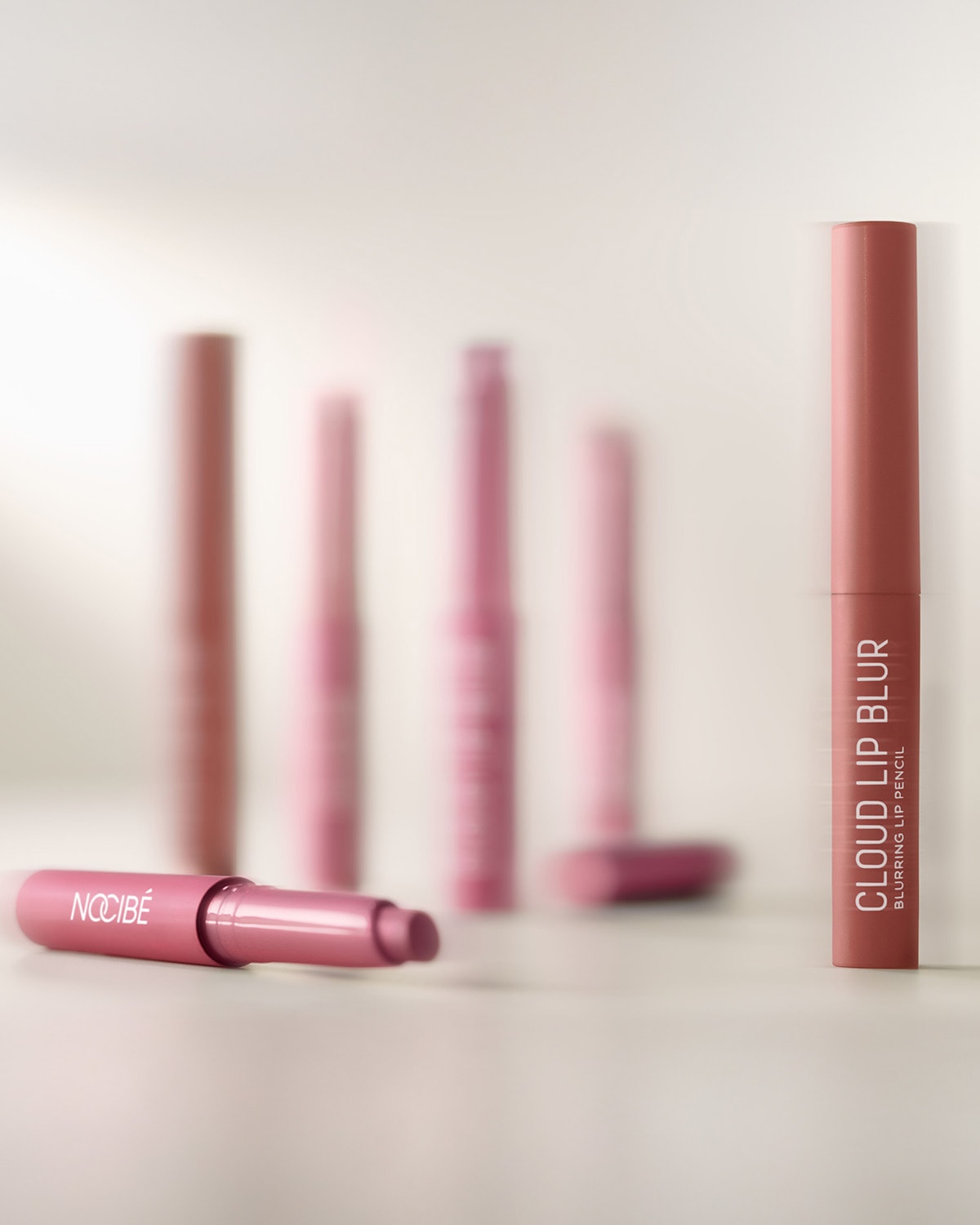 Découvrez le crayon à lèvres Nocibé Cloud Lip Blur, un crayon est debout et un autre couché, tous deux dans des tons roses.