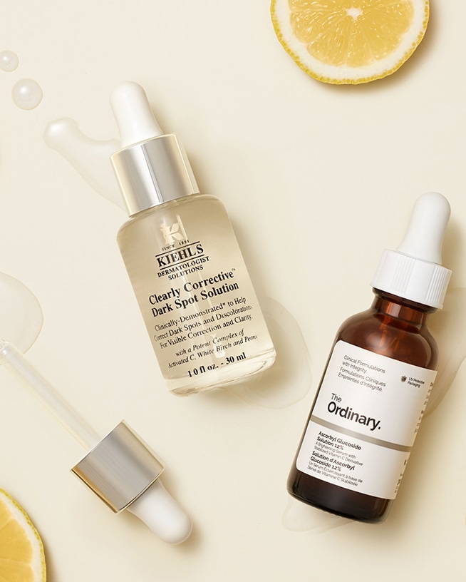 Deux sérums à la vitamine C avec pipette, accompagnés de tranches de citron fraîches sur un fond clair. Cet actif tendance contribue à un teint lumineux et uniforme et s’intègre facilement à toutes les routines de soin de la peau.